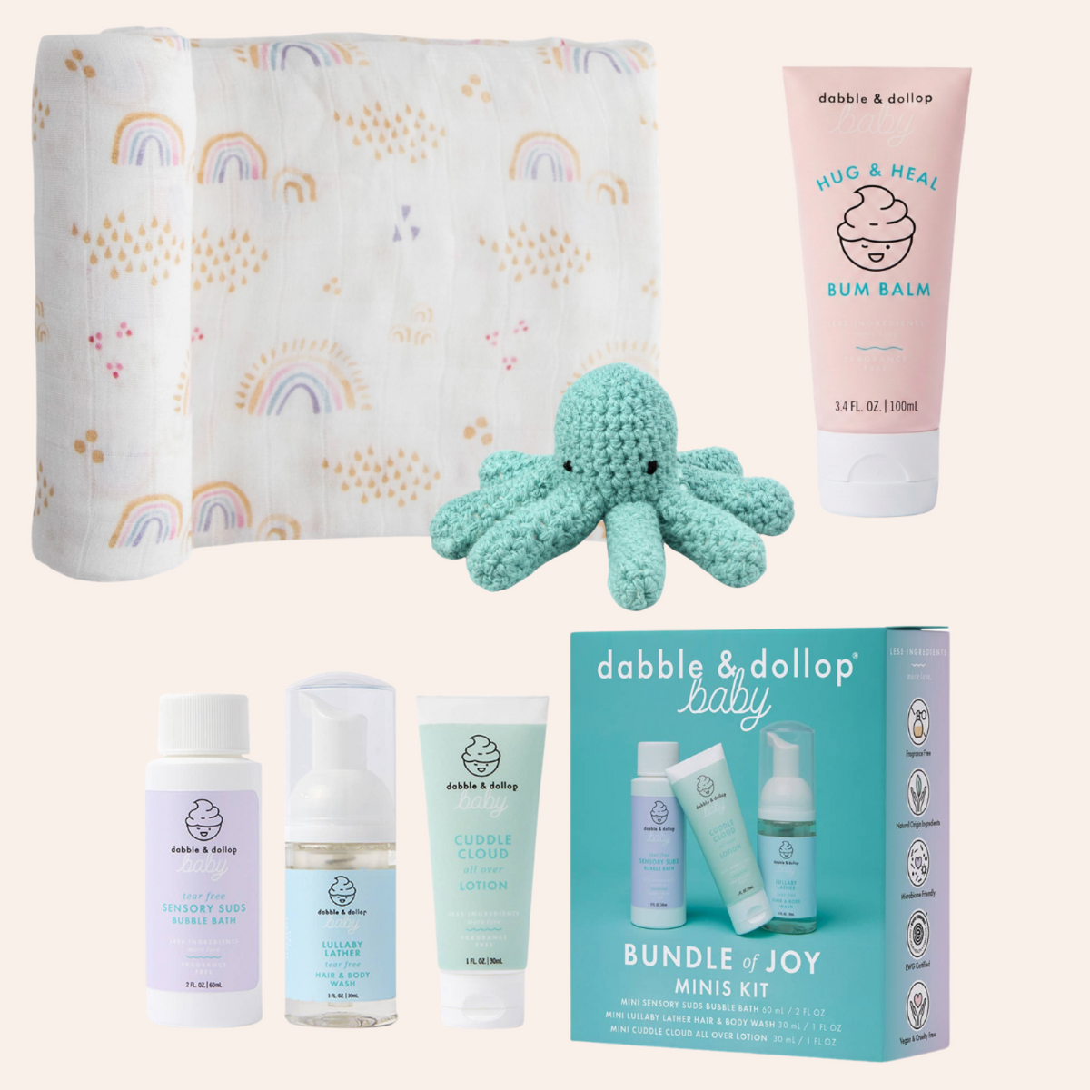 A baby care bundle set from dabble & dollop baby, featuring a muslin swaddle blanket with a rainbow and cloud pattern, a mint green crocheted octopus toy, a pink 'Hug & Heal Bum Balm' tube, three small toiletry bottles, and a turquoise 'Bundle & Joy Minis Kit' box, all arranged on a light beige background. Little Birdies Rainbows & Raindrops Gift Set for Baby Girl Newborn 